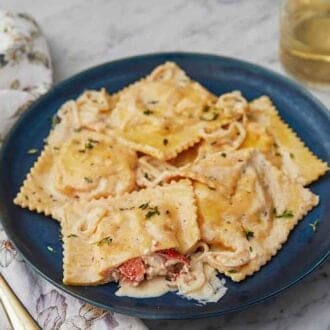 A plate of lobster ravioli with one cut, showing the lobster filling.
