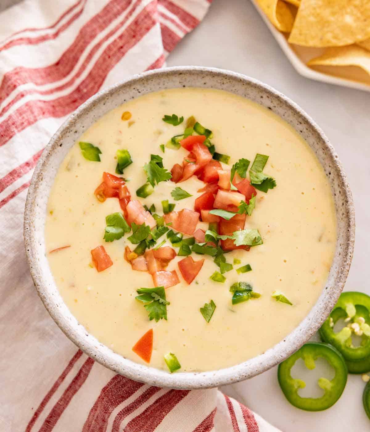 Overhead view of queso dip with diced tomatoes and cilantro on top.