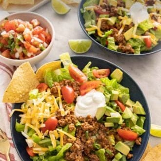 Pinterest graphic of two bowls of taco salad with a small bowl of pico de gallo beside it.