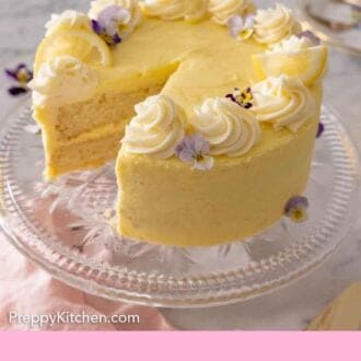 Pinterest graphic of a homemade lemon cake on a clear cake stand with a slice cut out.