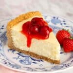 A slice of cheesecake with berry sauce on top.