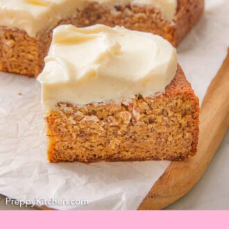Pinterest graphic of a slice of banana cake on a parchment lined wooden serving board with the rest of the cake behind it, out of focus.