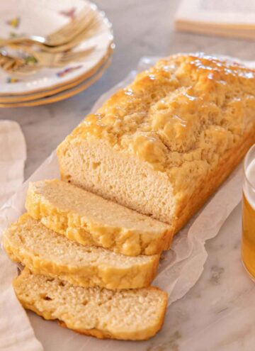 A loaf of beer bread with three slices cut in front of the loaf.