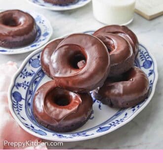 Pinterest graphic of a platter of chocolate donuts with a glass of milk and more donuts in the background.