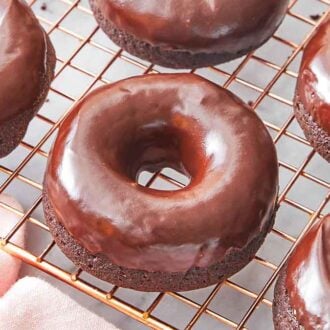 Multiple chocolate donuts on a wire cooling rack.