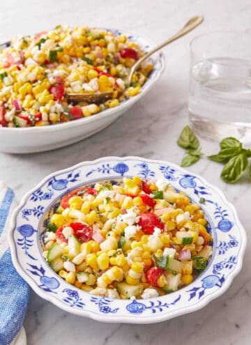 A plate of corn salad with a serving platter in the background.