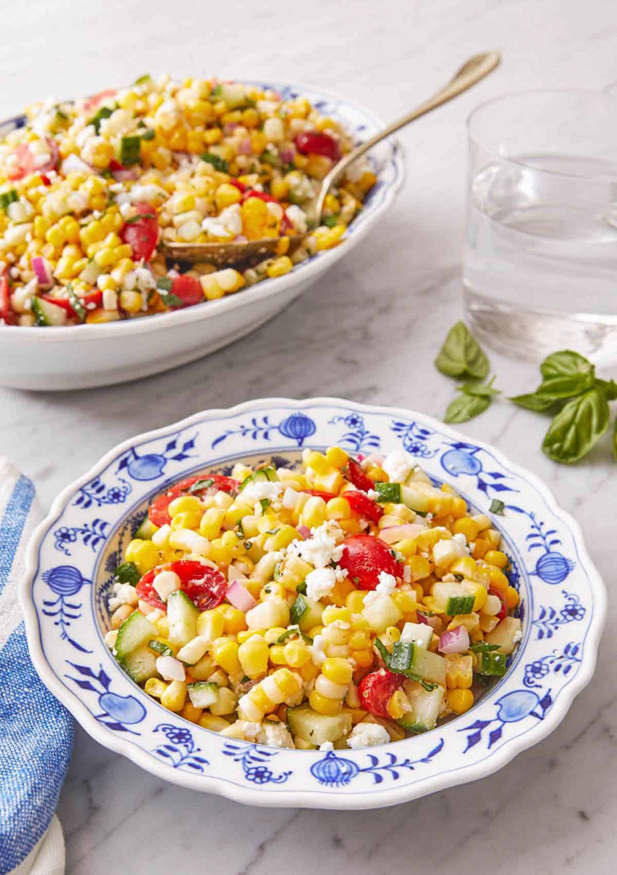 A plate of corn salad with a serving platter in the background.