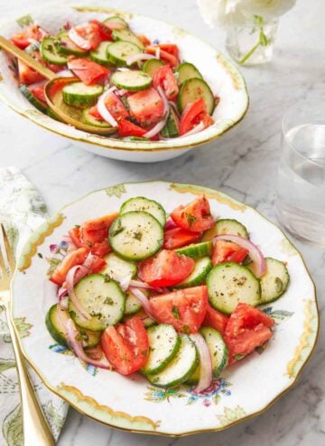A plate of cucumber tomato salad with a platter full in the background.