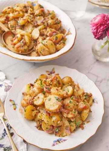 A plate of German potato salad with a serving platter in the background.