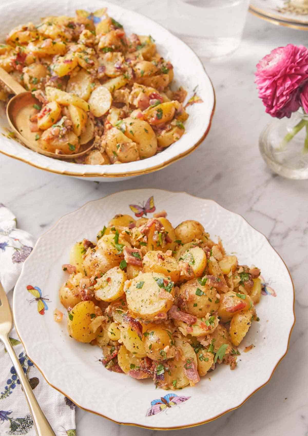 A plate of German potato salad with a serving platter in the background.