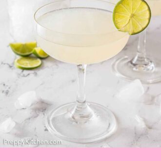Pinterest graphic of a glass of gimlet with a slice of lime on the rim with another drink, container of ice, and limes behind it.