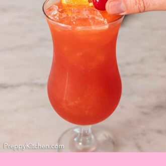 Pinterest graphic of a cherry being placed into a cocktail glass of hurricane drink.