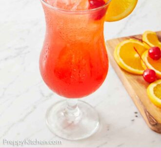 Pinterest graphic of a hurricane drink with a cherry and orange slice garnish. More garnish beside it on a wooden board.