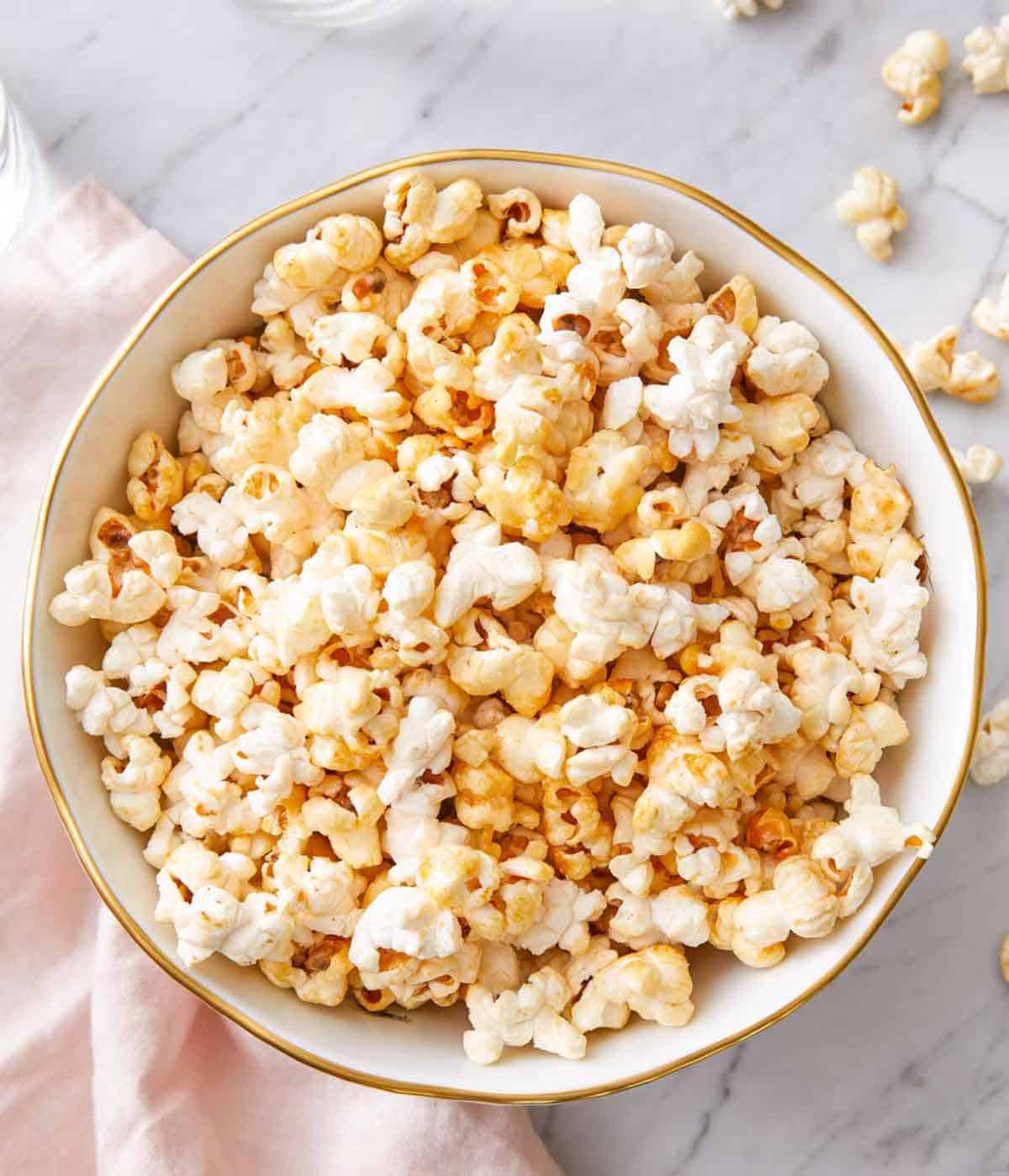 Overhead view of a bowl of kettle corn with some scattered on the counter.