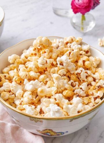 A bowl of kettle corn by a pink linen napkin.