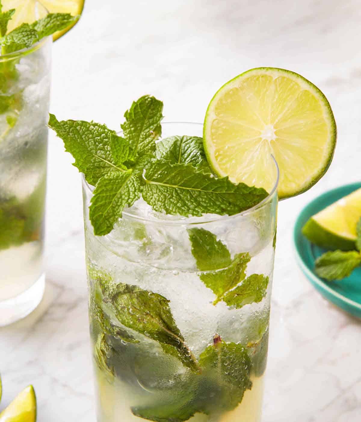A close view of a glass of mojito with fresh mint and a slice of lime as garnish.