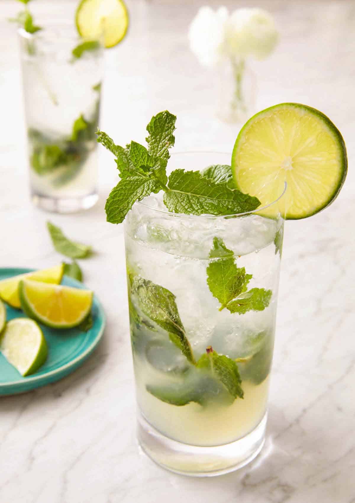 A glass of mojito with a lime and mint garnish on the rim of the glass.