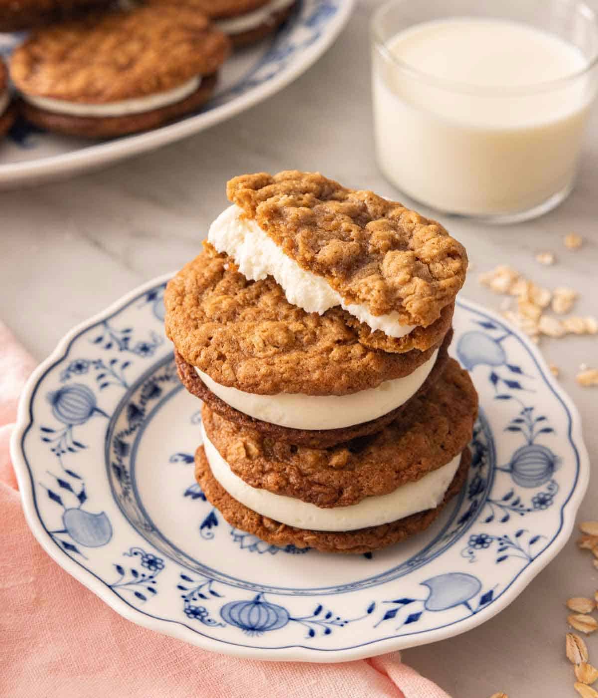 A plate with three oatmeal cream pies in a tall stack with the top one cut in half.