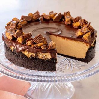 A cake stand with a peanut butter cheesecake on top, with a slice removed.