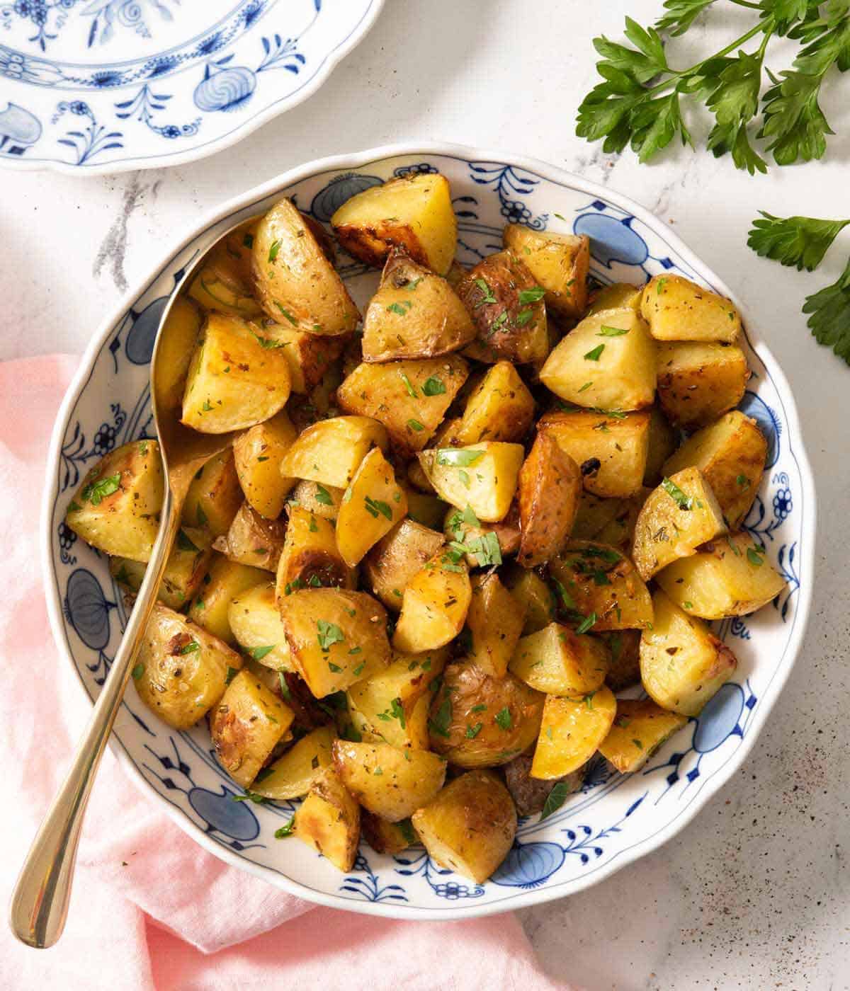Overhead view of a bowl of roasted potatoes with a spoon in the bowl.