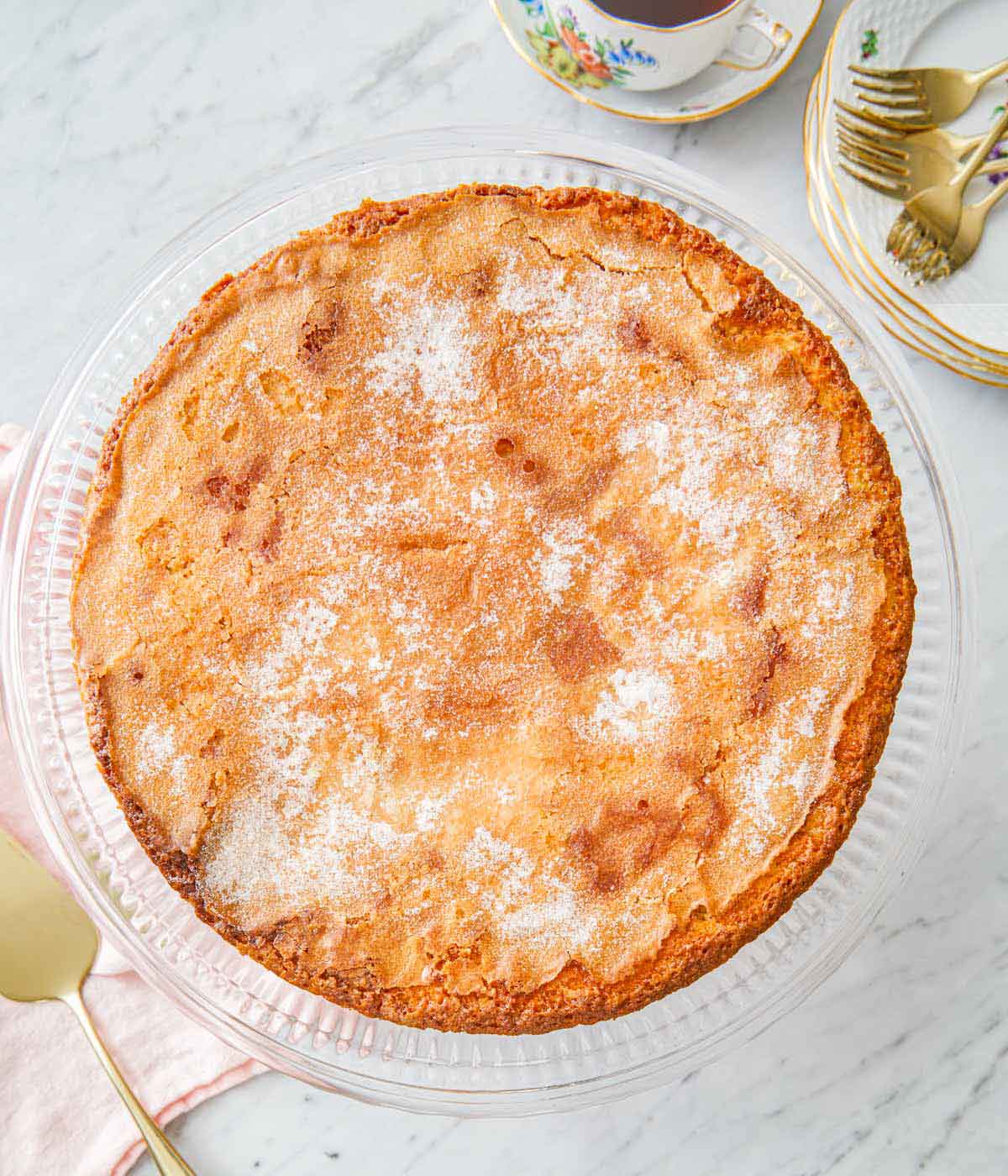 Overhead view of an olive oil cake on a clear cake stand.