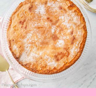 Pinterest graphic of an overhead view of an olive oil cake on a clear cake stand.