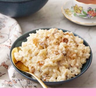 Pinterest graphic of a bowl with rice pudding and a spoon tucked in and a cup of tea in the background.