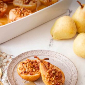 Pinterest graphic of a plate with two baked pears with granola on top with a baking dish with more in the background.
