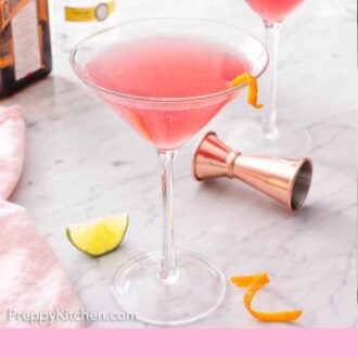 Pinterest graphic of two glasses of Cosmopolitan cocktails with the alcohol bottles in the background and garnish in the front.