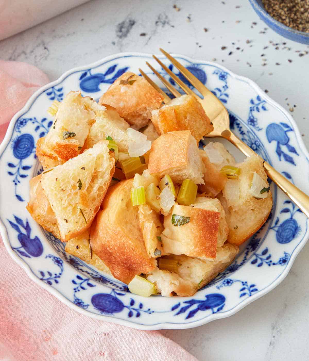 A small plate of stuffing with a gold fork.