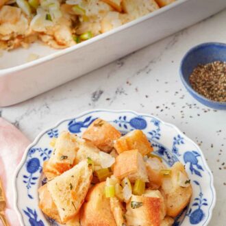 Pinterest graphic of a plate of stuffing with some ground pepper and a baking dish of stuffing in the back.