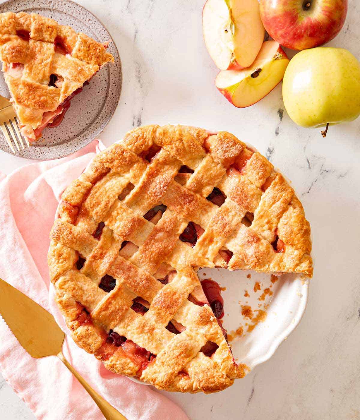 Overhead view of an apple cranberry pie with a slice cut out and plated.