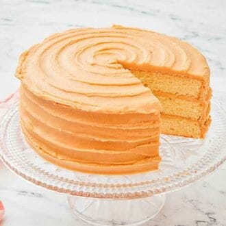 A cake stand with a caramel cake on top, a slice removed and plated on the side.