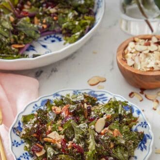 Pinterest graphic of a plate of kale salad with a small bowl of almonds and the rest of the salad in the background.