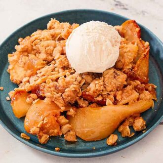 A blue plate with a serving of pear crisp with a scoop of ice cream on top.
