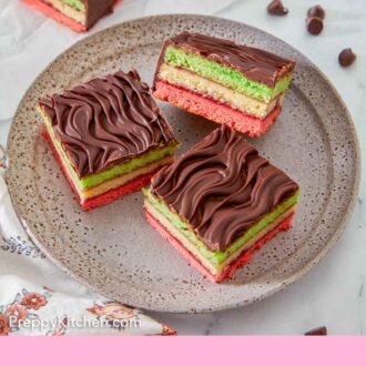 Pinterest graphic of a plate with three pieces of rainbow cookies with one angled up, showing the distinct colored layers.