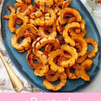 Pinterest graphic of an overhead view of an oval blue serving platter filled with roasted delicata squash.