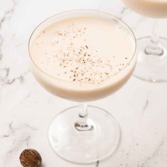 A coupe glass of Brandy Alexander with fresh nutmeg shaved on top.