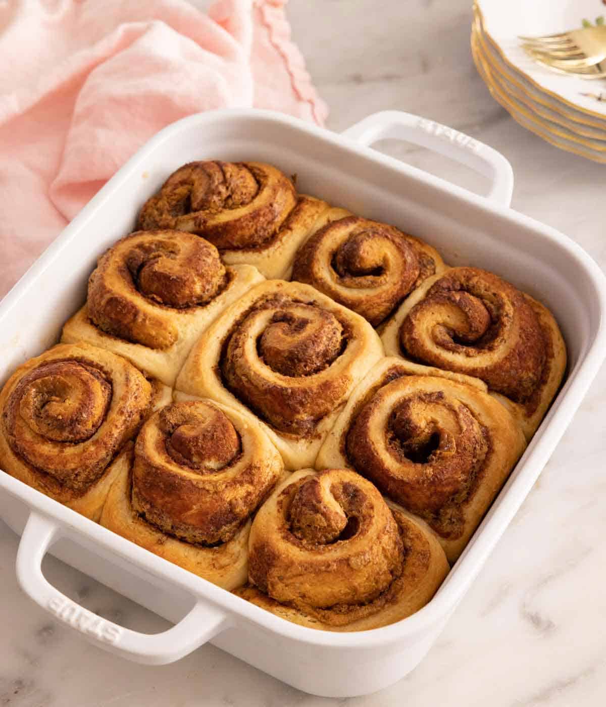 A square white baking dish with nine dulce de leche cinnamon rolls.