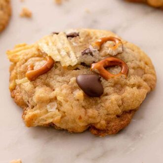 A kitchen sink cookie with crushed chips, pretzels, and chocolate chips on top.