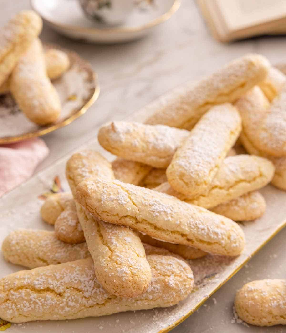 An oval platter full of ladyfingers with powdered sugar dusted on top.