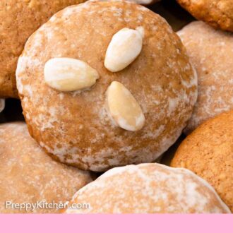Pinterest graphic of a close up view of one Lebkuchen on top of more, with three almonds on top of the cookies.