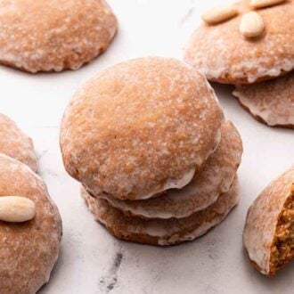 Multiple Lebkuchen cookies on a marble surface with a stack of three in the middle.