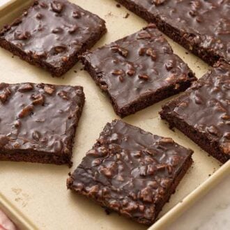 A sheet pan with a Texas sheet cake with multiple pieces cut into squares.