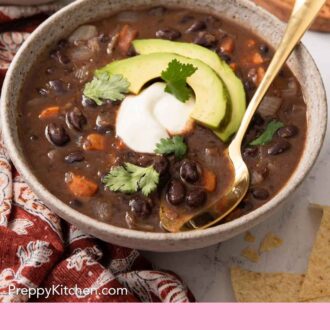 Pinterest graphic of a bowl of black bean soup with sliced avocado, cilantro, and sour cream garnish.