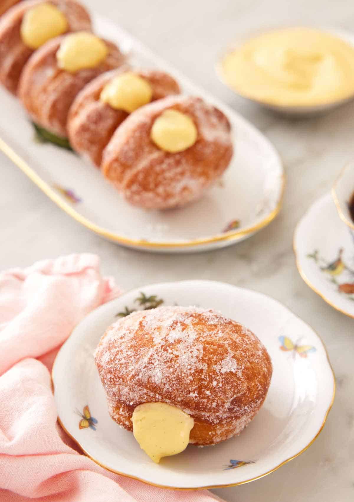 A plate with a bomboloni with a platter with four more in the background.