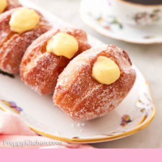 Pinterest graphic of a platter of bomboloni with a cup of coffee in the background.