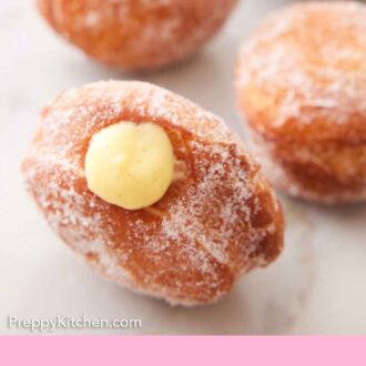 Pinterest graphic of a close up of an upright bomboloni with pastry cream coming out the top.