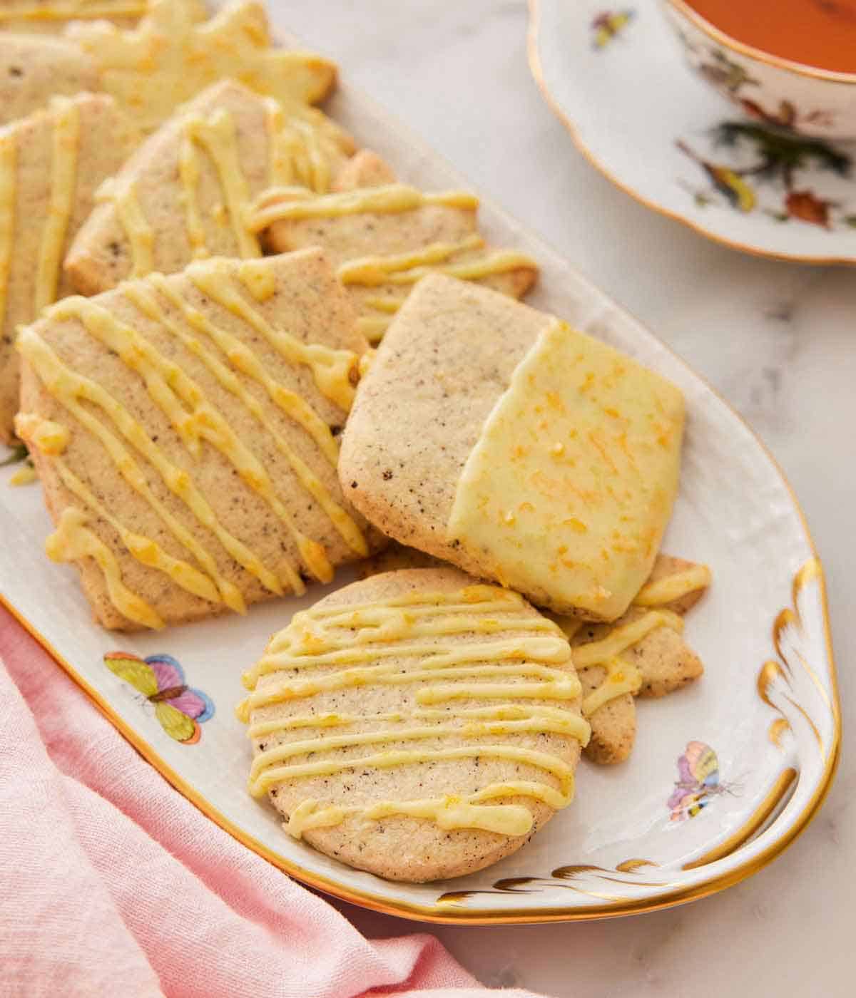 A serving platter with multiple browned butter-earl grey cookies with a pink linen napkin beside it.