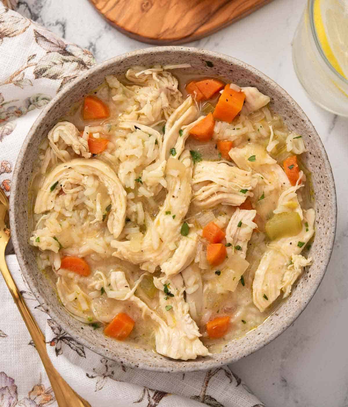 Overhead view of a bowl of chicken and rice soup with chopped parsley garnish.